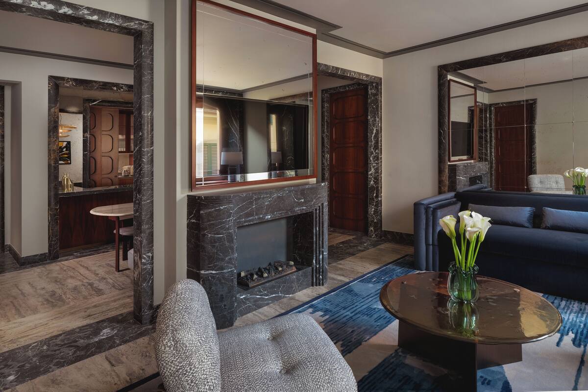 Una sala de estar moderna con chimenea, un sofá, una mesa de centro con un jarrón de flores y un espejo grande.