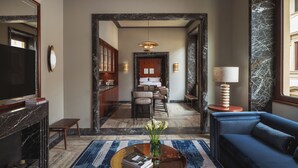 A modern hotel lobby with a blue sofa, a coffee table with books, a TV, and a fireplace. - Palazzo Ottaviani Luxury Apartments (Florence)