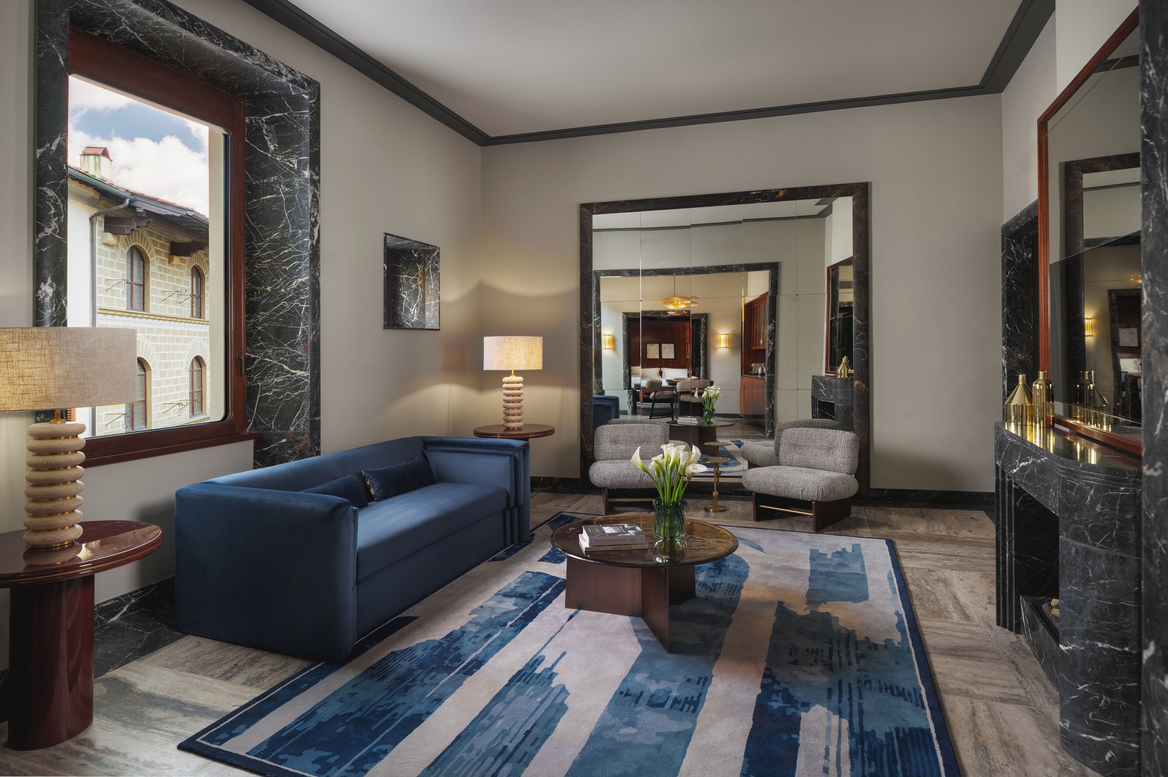A modern living room with a blue sofa, a coffee table, and a patterned rug.