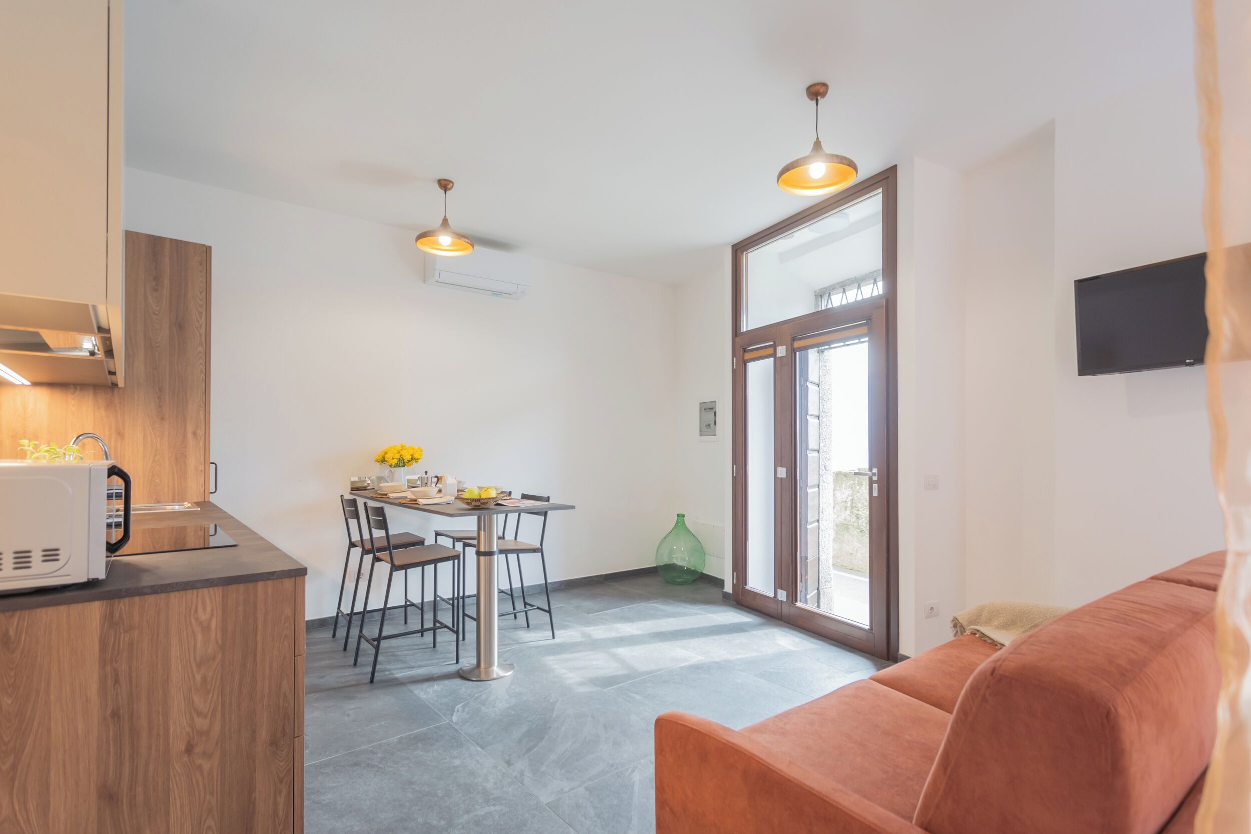 A compact living space with a kitchenette, dining area, and a sofa.