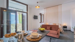 Una sala de estar moderna con un sofá, una mesa de comedor con alimentos para el desayuno y un ventanal con vistas.