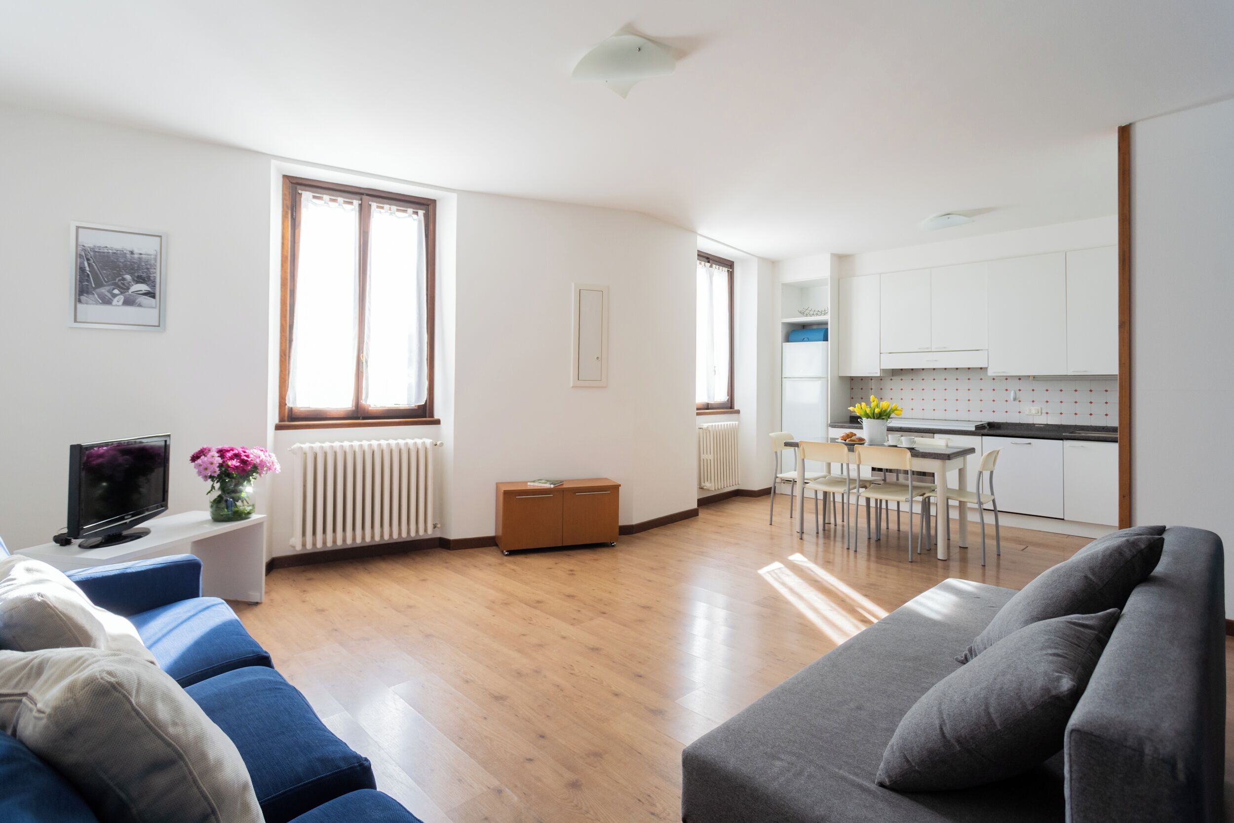 Un soggiorno moderno con divano, televisione e zona pranzo con tavolo e sedie.