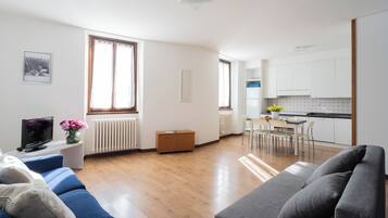 Un soggiorno moderno con divano, televisione e zona pranzo con tavolo e sedie.