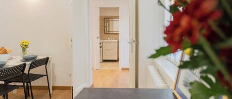 A modern apartment with a dining area, a kitchen, and a bathroom.