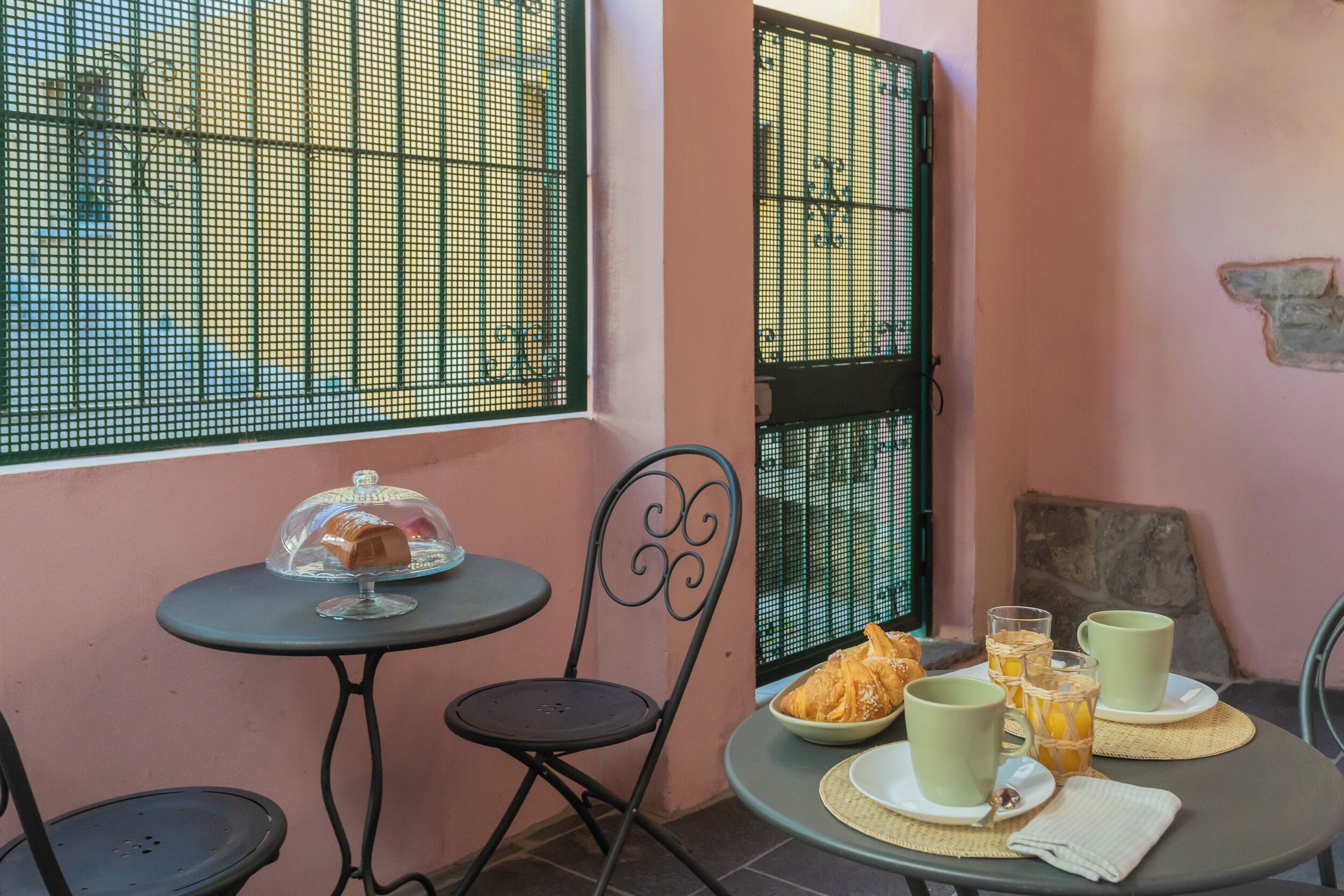 A small dining area with a table set for two, a chair, and a window with a metal screen.