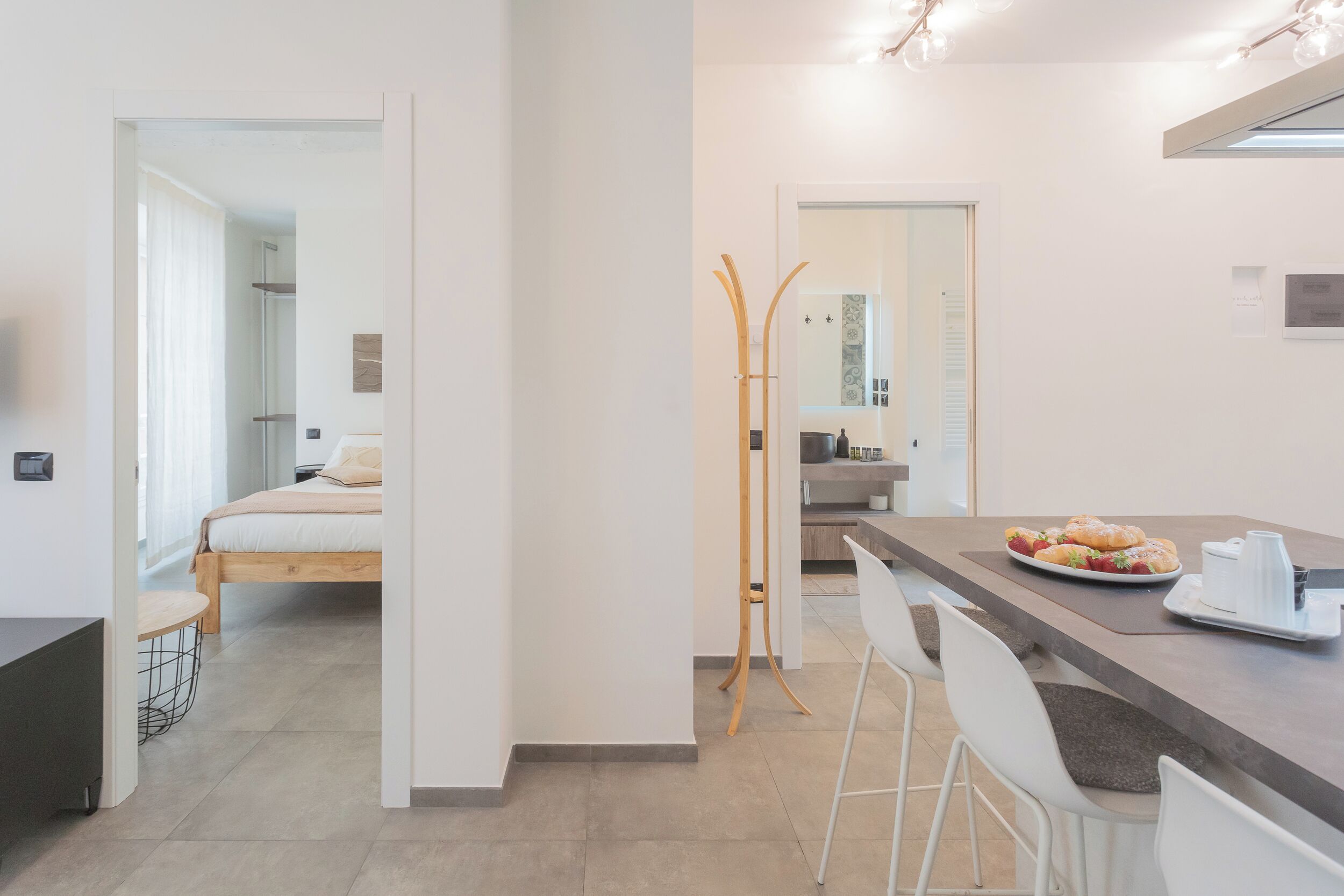 A modern hotel room with a bed, a small table, and a breakfast tray with pastries.