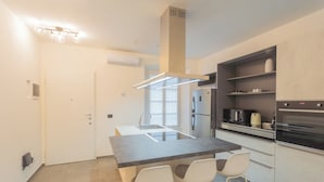 A modern kitchen with a central island, bar stools, a built-in oven, and a microwave. - Enchanted Como Lake - City Apartment by Rent all Como (Como)