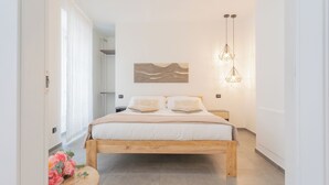 A bedroom with a wooden bed, a wall-mounted abstract art piece, and two hanging pendant lights. - Enchanted Como Lake - City Apartment by Rent all Como (Como)