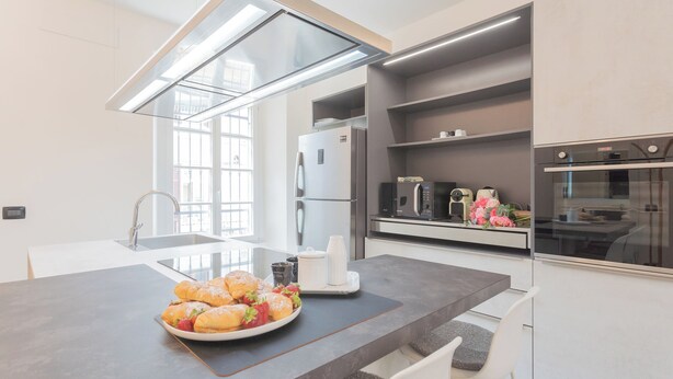 A modern kitchen with a central island, built-in appliances, and a large window. - Enchanted Como Lake - City Apartment by Rent all Como (Como)