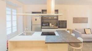 A modern kitchen with a central island, built-in oven, and a dining area with a sofa and chairs. - Enchanted Como Lake - City Apartment by Rent all Como (Como)
