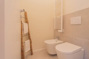 Un baño con una escalera de madera, un bidé y un inodoro.