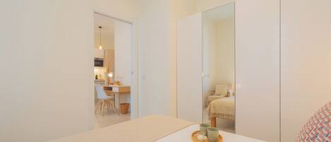 A minimalist bedroom with a bed, bedside table, and a large mirror.