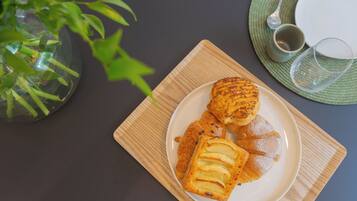 Un plato de pasteles sobre una bandeja de madera, un vaso de agua y una taza en una mesa con un mantel individual verde.