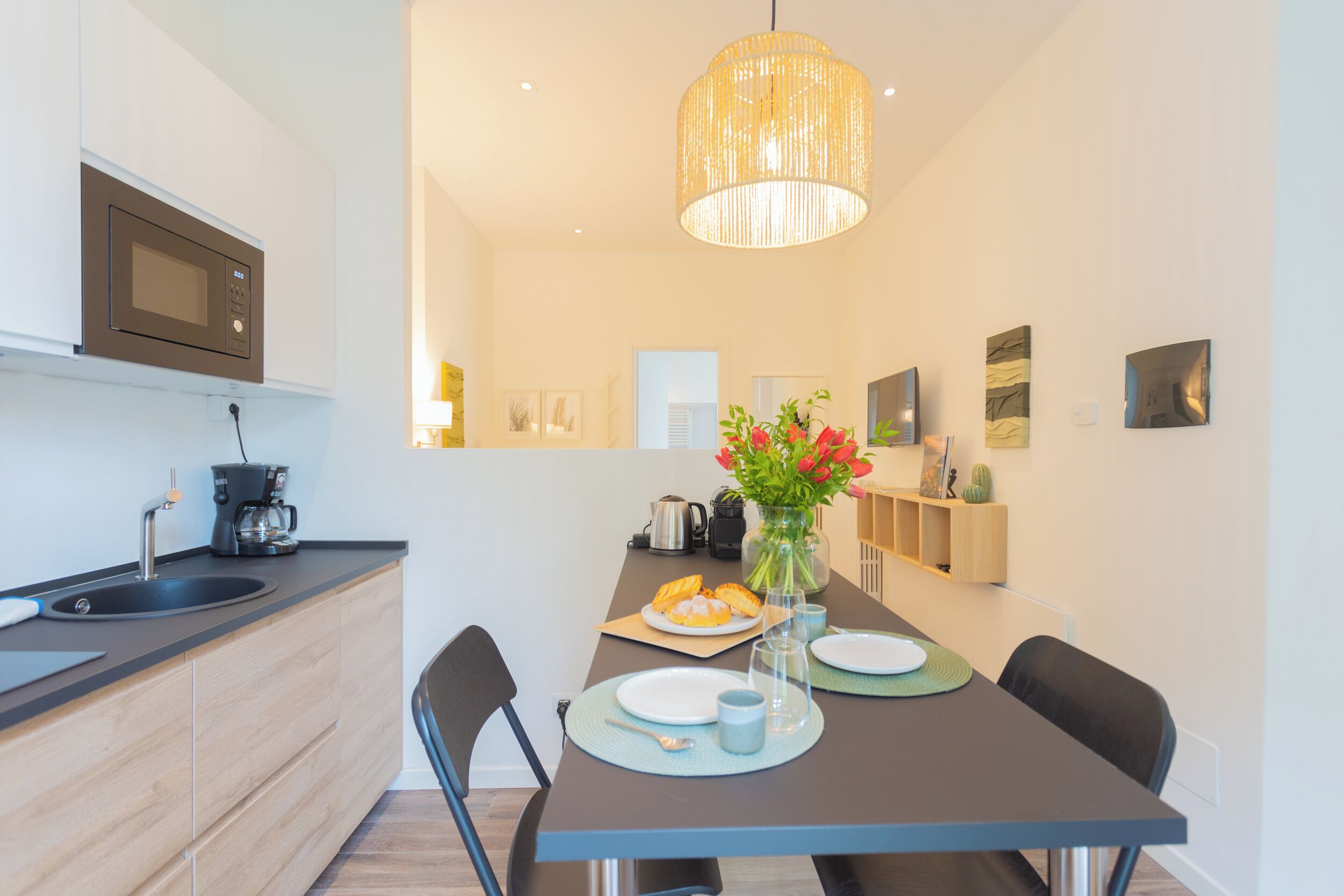 A modern kitchen with a built-in microwave, a coffee maker, and a dining area with a table set for two.