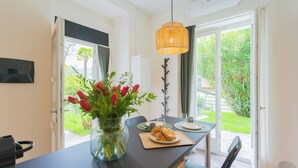 Una cocina moderna con comedor, un jarrón de tulipanes rojos y vistas al jardín a través de la puerta abierta.