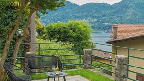 Terraza con dos sillas y una mesa, con vistas a un lago y colinas.