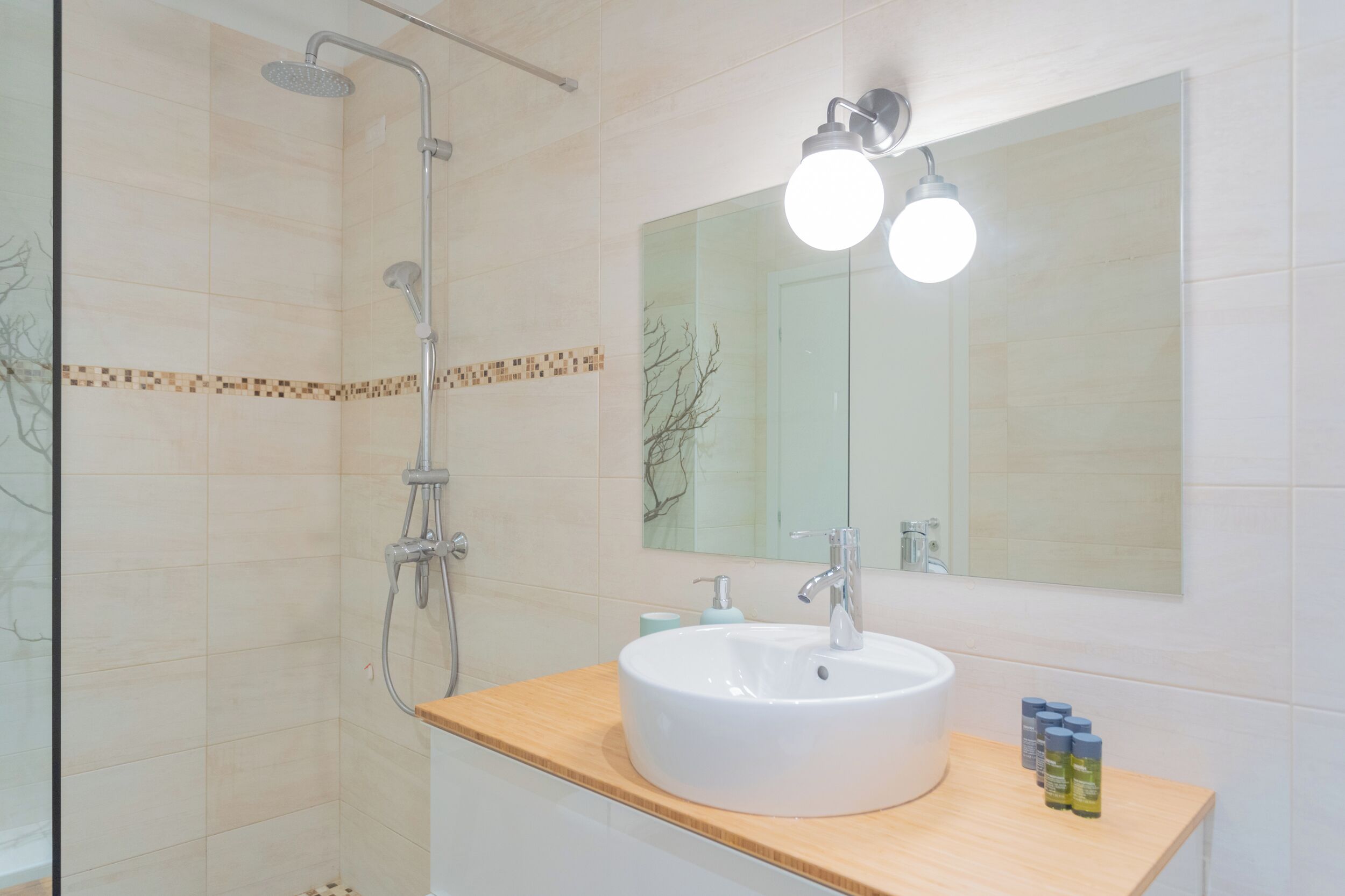 A bathroom with a white sink, a mirror, and a shower.