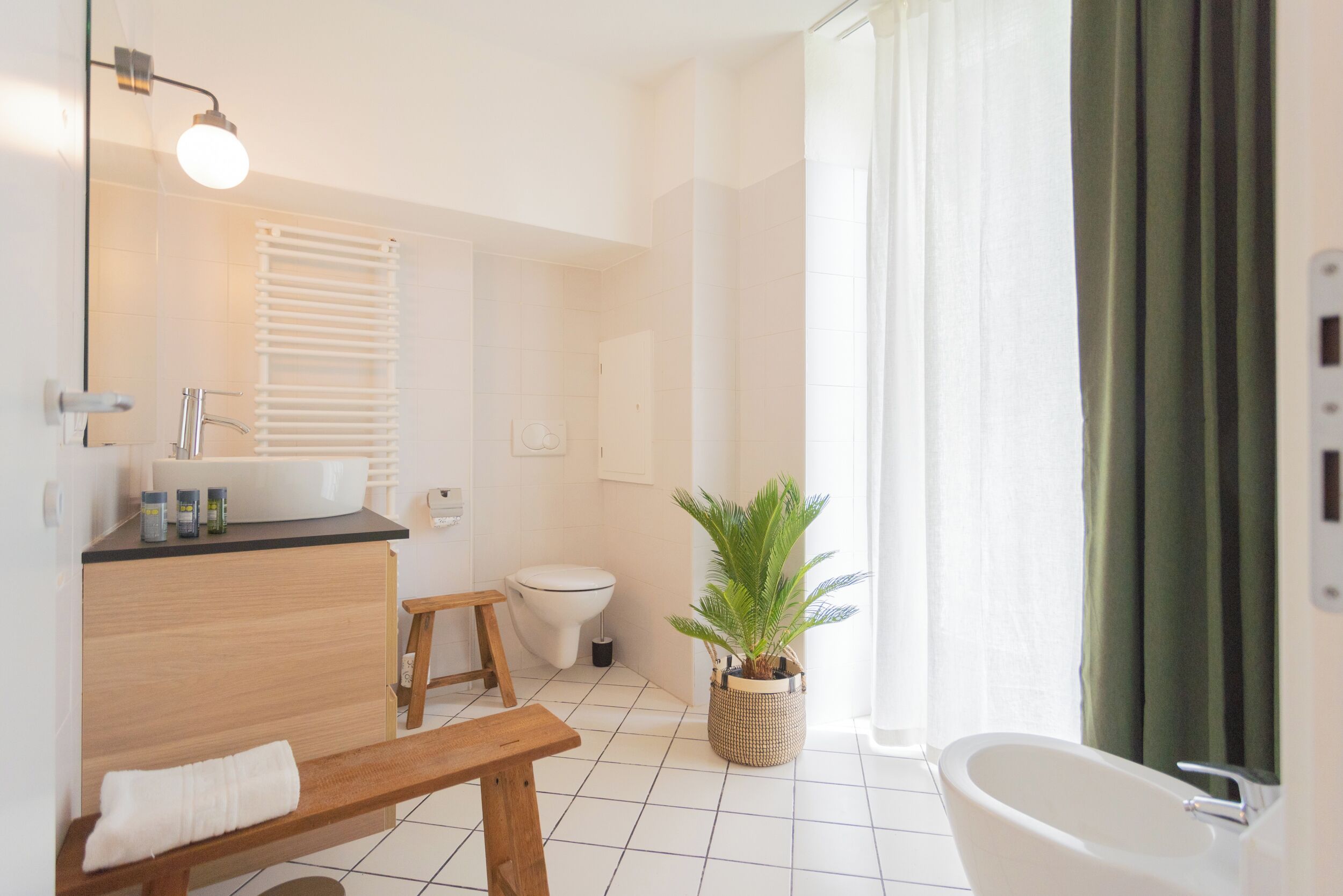 Une salle de bain moderne avec un banc en bois, un lavabo, des toilettes et une baignoire.