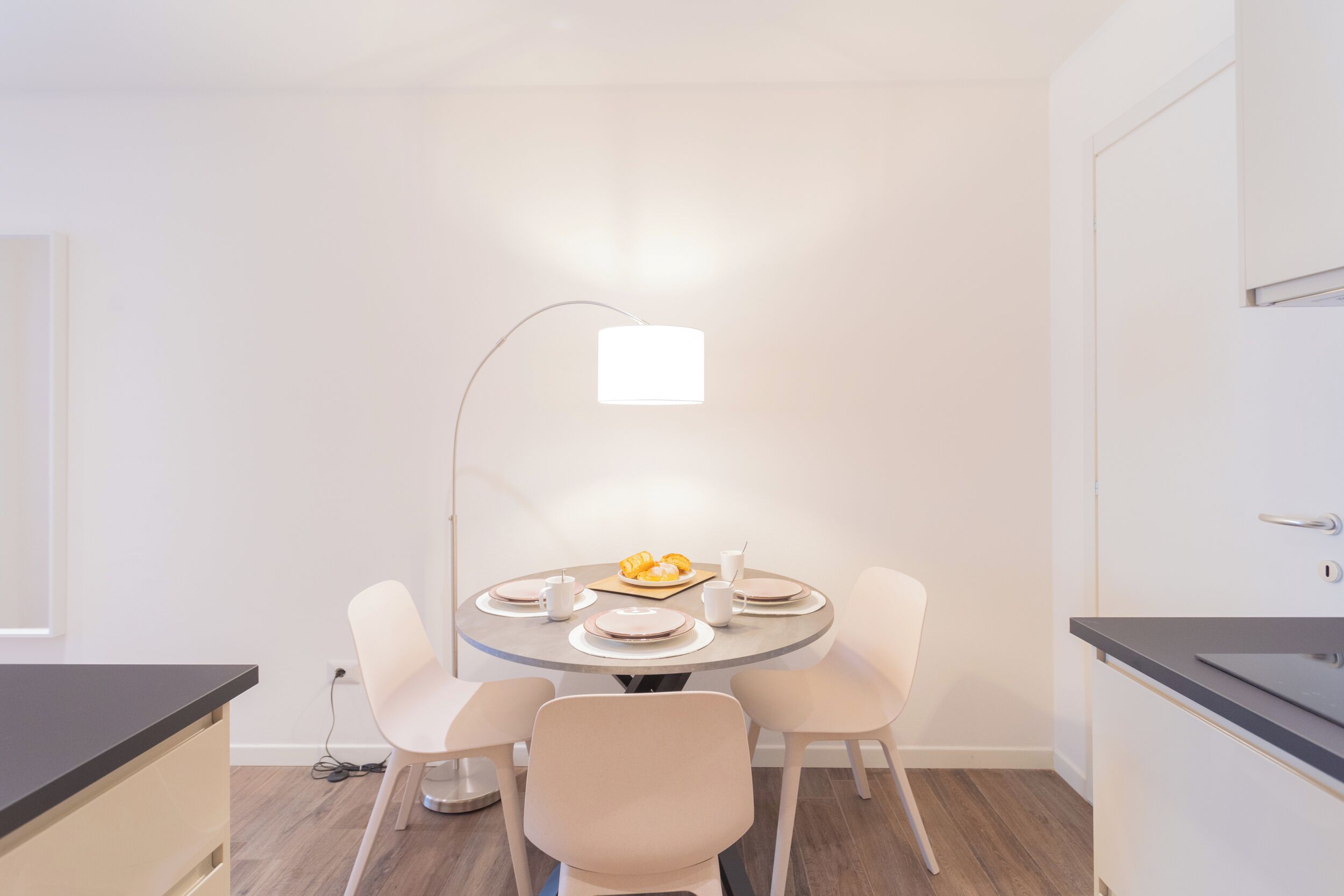 Ein moderner Essbereich mit einem runden Tisch, vier Stühlen und einer Lampe.