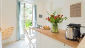 Una cocina moderna con encimera de madera, cafetera, un florero con flores y vistas al exterior.
