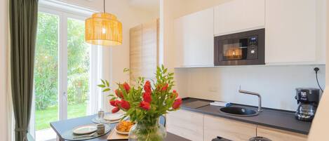 A modern kitchen with white cabinets, a black microwave, and a coffee maker.