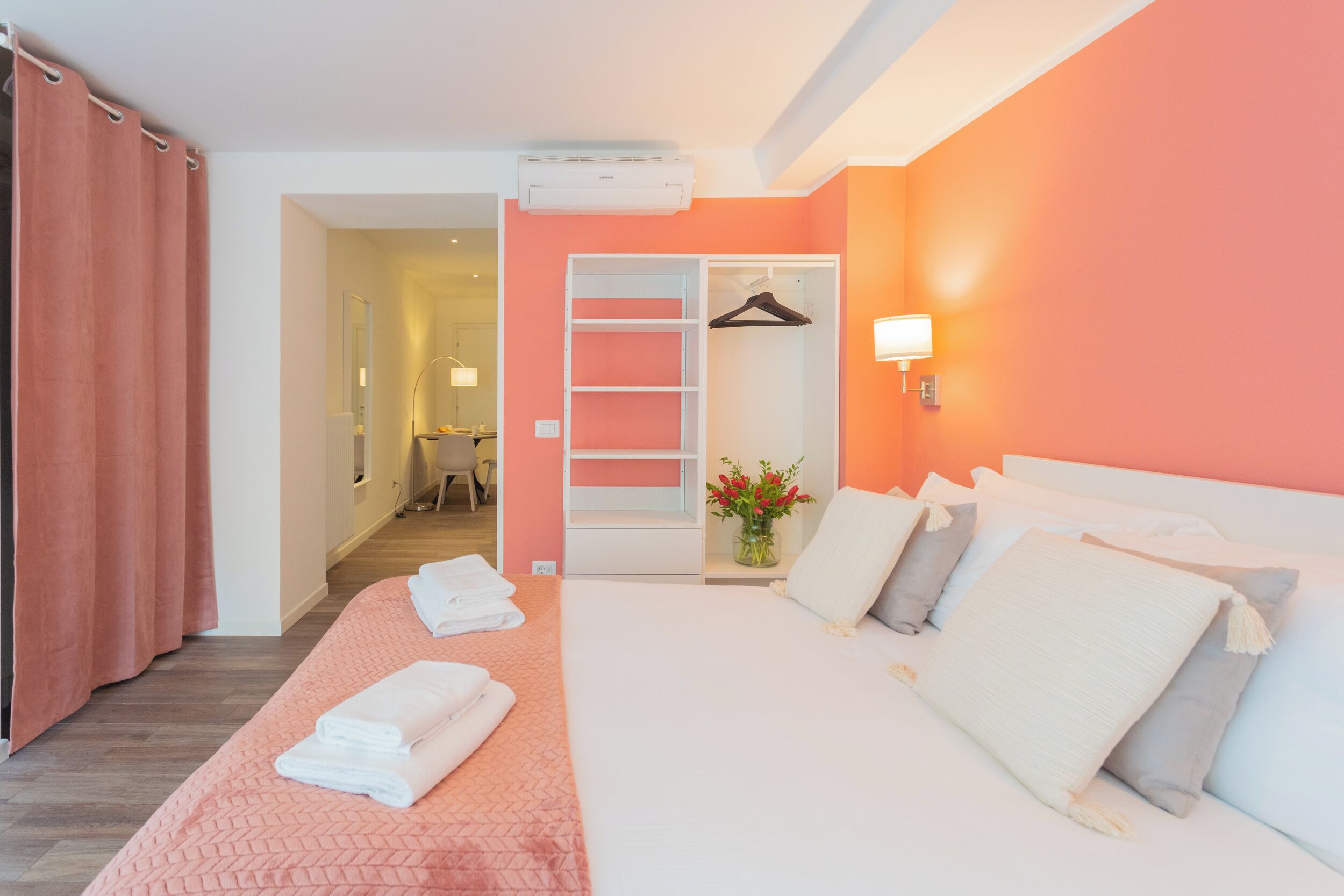 Una habitación de hotel con cama, armario, espejo y baño a la vista.