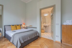 A bedroom with a bed, bedside table, lamp, and a view into the bathroom. - Garibaldi's Balcony by Rent all Como (Como)