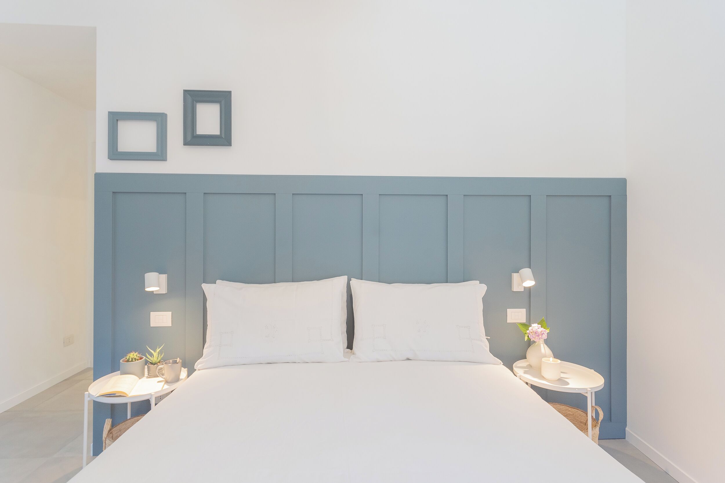 Un dormitorio con una cama grande, dos mesitas de noche y un aplique de pared.