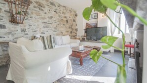 A living room with a stone wall, a white sofa, a wooden coffee table, and a television. - Giuliano's House - Amazing Lake View by Rent all Como (Laglio)