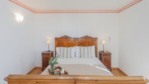 A neatly made bed with a wooden headboard, two bedside tables with lamps, and a small bedside table with a candle. - Giuliano's House - Amazing Lake View by Rent all Como (Laglio)