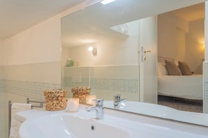 A bathroom with a large mirror, a sink, and a toilet. There are two candles on the sink and a towel rack beside the toilet. - Il Timone by Rent all Como (Colonno)