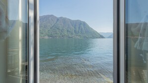 Vista a través de una ventana de un lago de montaña con aguas cristalinas y una montaña al fondo.