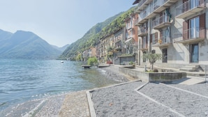 Un hotel frente al lago con balcones que dan a la orilla, rodeado de montañas.