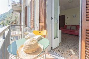 A balcony with a table, a chair, and a straw hat. - Il Timone by Rent all Como (Colonno)