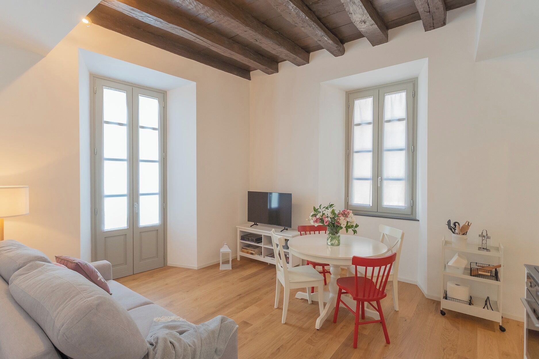 Una sala de estar acogedora con un sofá, una mesa de comedor con sillas, un televisor y una estantería.