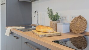 A modern kitchen with a wooden countertop, a loaf of bread, a plant, and a woven basket. - Isola Felice Grandate by Rent all Como (Grandate)