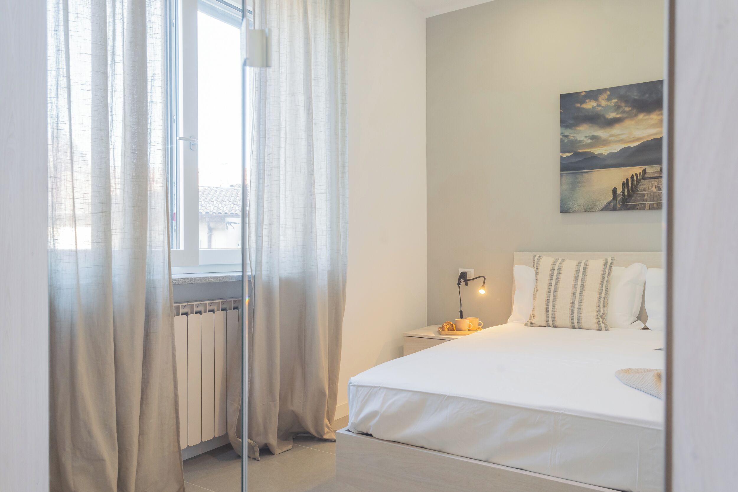 Ein Schlafzimmer mit einem Bett, einem Nachttisch, einer Lampe und einem Bild an der Wand.