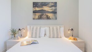 A neatly made bed with pillows, a bedside table with a lamp, a magazine, and a tray with a cup and a pastry. - Isola Felice Grandate by Rent all Como (Grandate)
