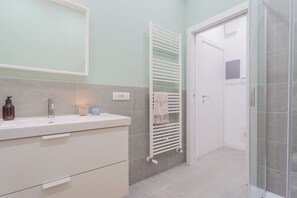A bathroom with a white sink, a towel rack, and a shower area.
