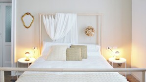 A neatly made bed with white linens and two pillows, a bedside table with a lamp, and a wall-mounted heart-shaped mirror. - Via Anzi Como Apartments by Rent all Como (Como)