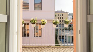 A balcony with hanging flower pots and a view of neighboring buildings. - Via Anzi Como Apartments by Rent all Como (Como)