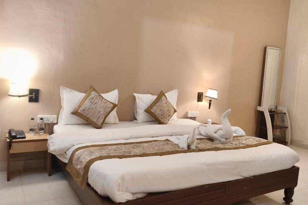 Un lit double avec du linge de lit blanc et des coussins décoratifs, des tables de chevet avec des lampes et un grand miroir au mur.