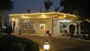 Entrada de hotel con un área exterior cubierta, puertas de vidrio y una zona de estar en el interior.
