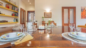 A dining room with a wooden table set for four, surrounded by bookshelves and a painting. - La Casa del Golfista by Rent all Como (Como)