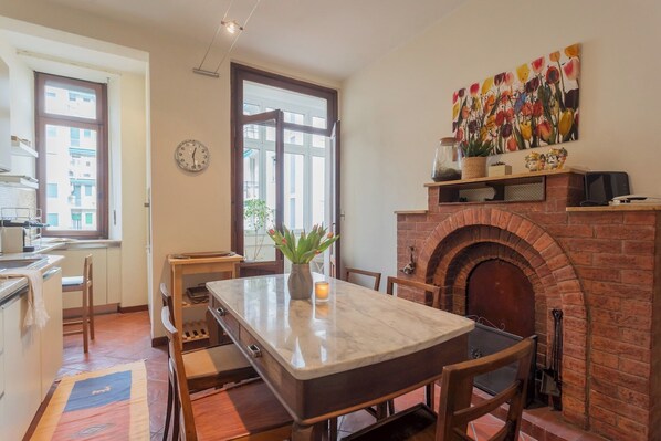 A kitchen with a marble countertop, a brick fireplace, and a dining area with wooden chairs. - La Casa del Golfista by Rent all Como (Como)