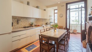 A modern kitchen with white cabinets, a tiled backsplash, and a dining area with a marble table and wooden chairs. - La Casa del Golfista by Rent all Como (Como)