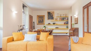 A living room with a yellow sofa set, a dining table, and a bookshelf with books and decorative items. - La Casa del Golfista by Rent all Como (Como)