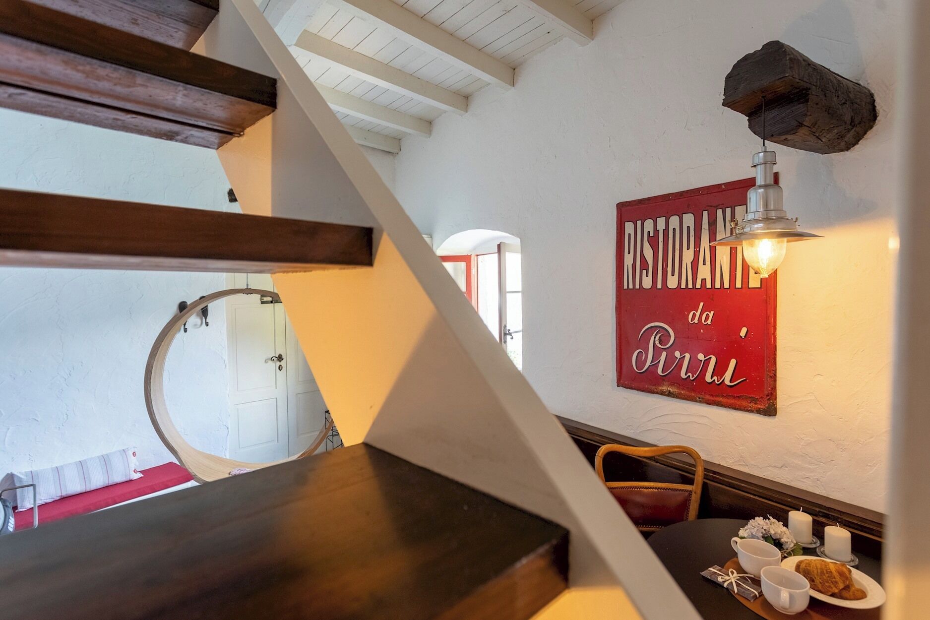 A dining area with a wooden table, a chair, a plate with food, a candle, and a wall sign reading "RISTORANZA da Pini".