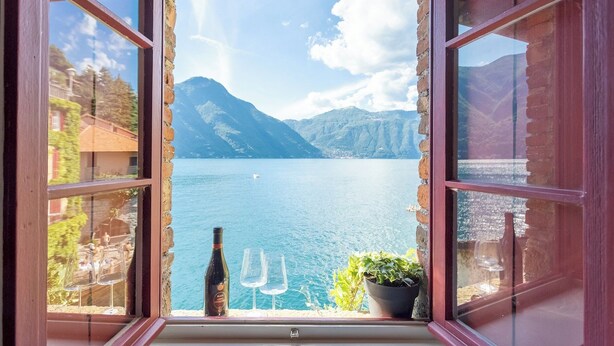 An open window with a view of a lake and mountains.