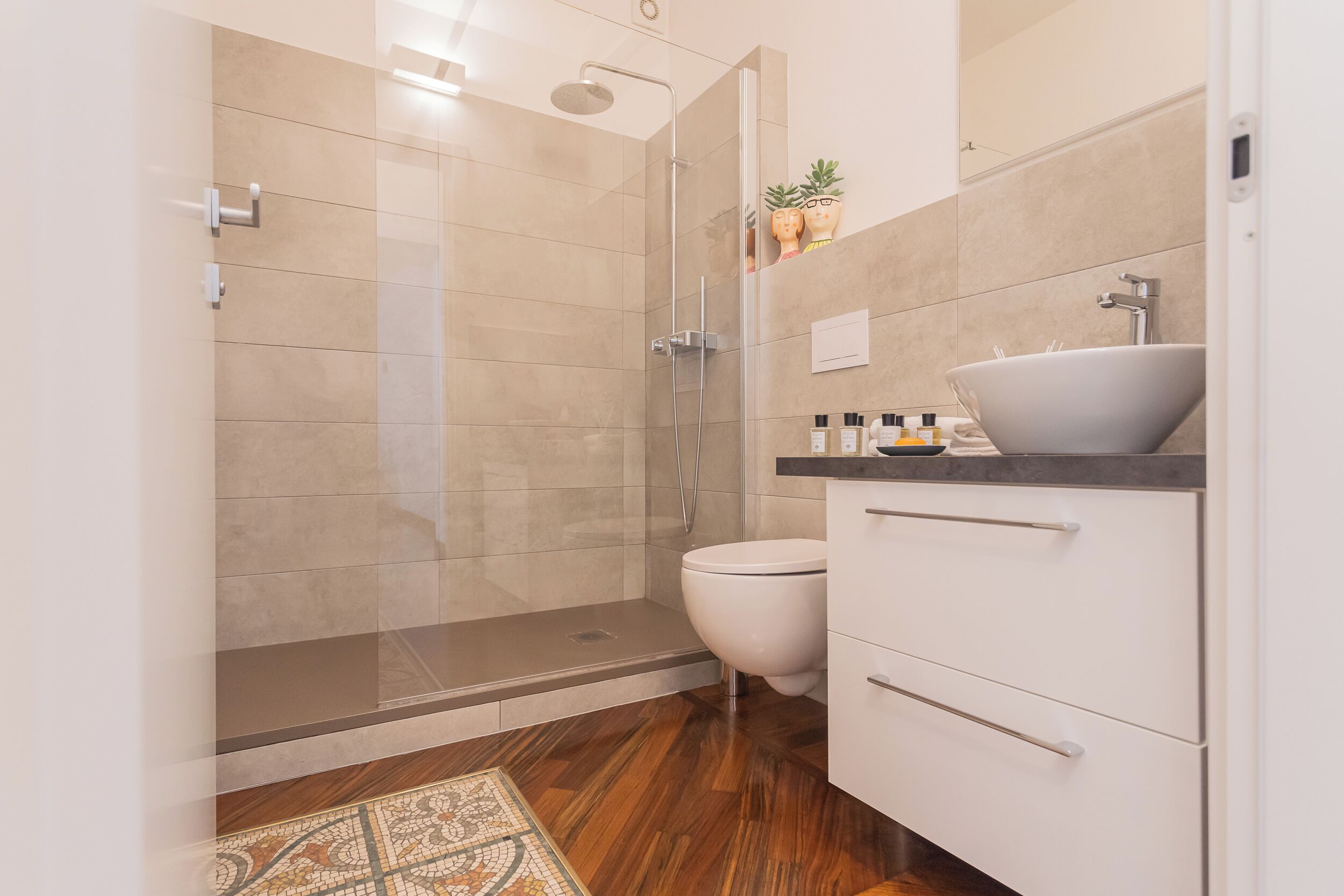 A modern bathroom with a glass-enclosed shower, a white toilet, and a white sink with a marble countertop.